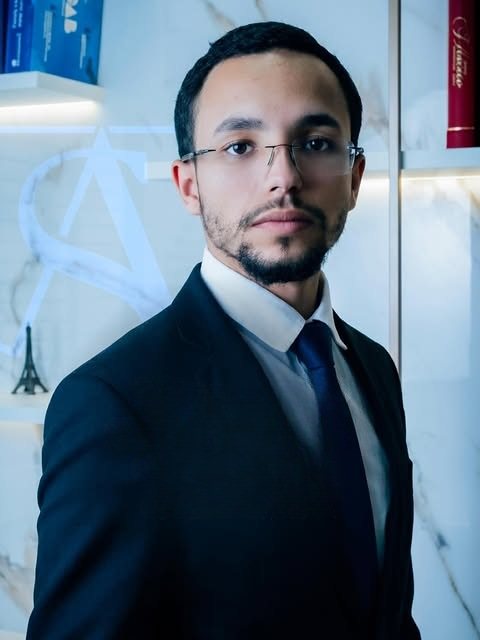 Allan Soares, advogado, de terno escuro em seu escritório